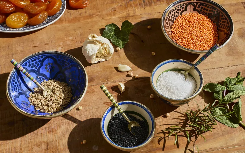 Bols de lentilles corail, de sel et de céréales avec de l’ail et de la menthe fraîche sur une table en bois